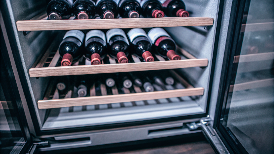A wine cooler with perfectly organized bottles of red and white wine.