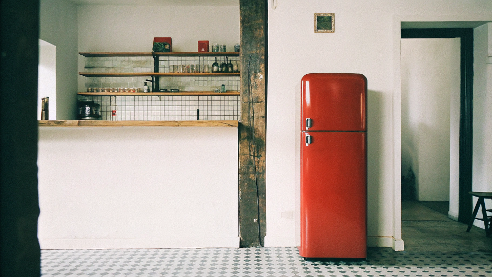 A bright red retro fridge placed strategically in a bar corne