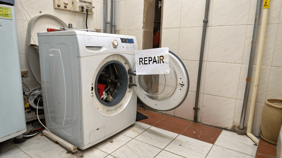Modern Appliance Repair A broken modern washing machine with a repair sign on it.