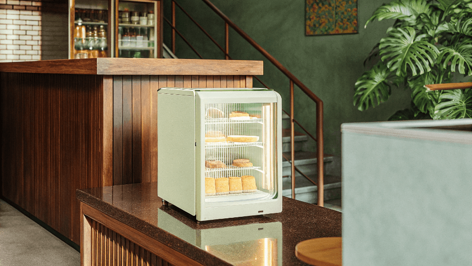 A stylish cream-colored countertop display fridge in a modern coffee shop.