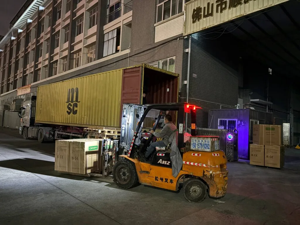 workers loading mini fridges into a shipping container at a factory in China