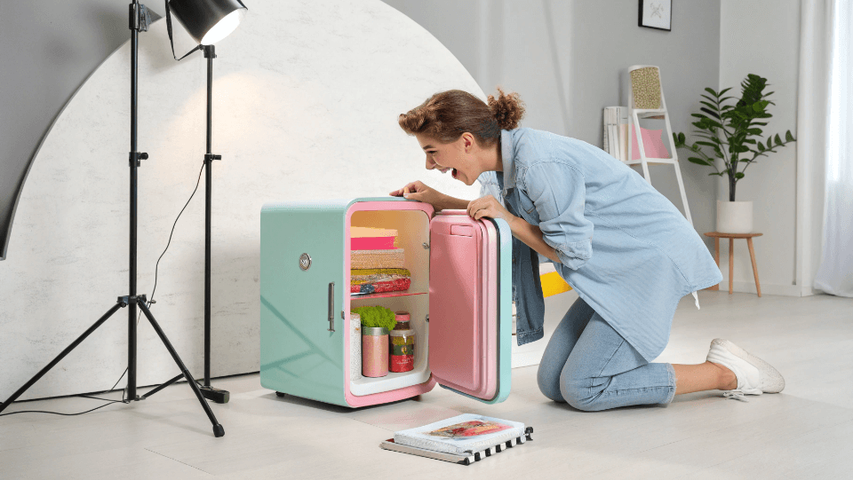 an influencer unboxing a colorful retro mini fridge in their studio